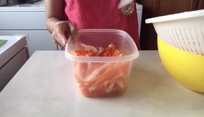Place the carrots and daikon in a container.