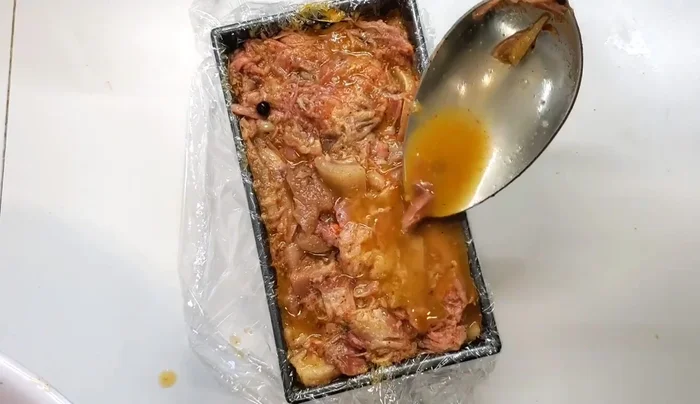 Line a bread tin or terrine mold with plastic wrap. Divide the meat into the molds, covering with stock.