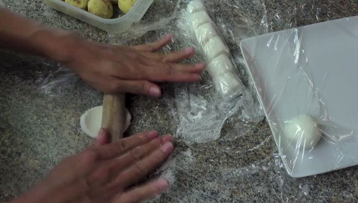 Roll each dough piece into a ball, then flatten into a disc. Place a mung bean ball in the center, and enclose it completely, ensuring no air is trapped. Gently roll into a smooth dumpling.