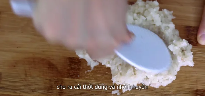 Using a rice ladle, mash the cooked sticky rice until mushy. Transfer to a sheet of plastic wrap, roll it flat to about 5 centimeters thick. (140.56)