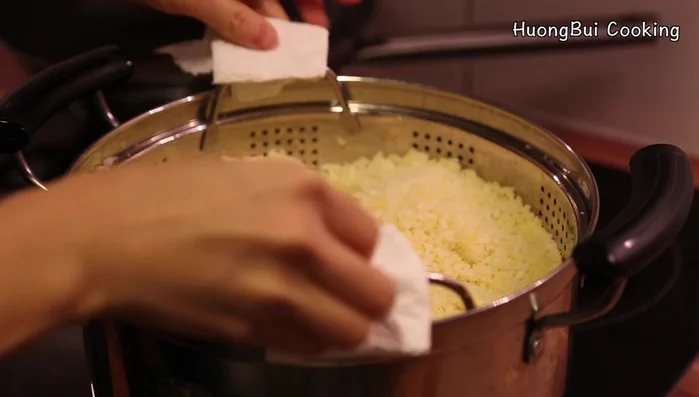 Transfer the steamed rice to a parchment paper-lined surface, spread it out, and add the remaining ground mung beans and sugar.
