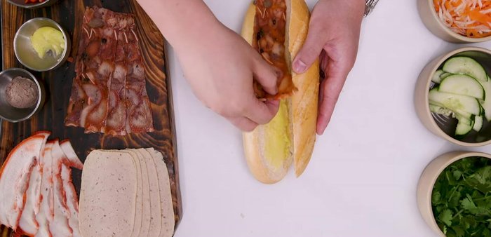 Assemble the Banh Mi (Southern Style): Generously layer mayonnaise on both sides of the baguette. Layer pate, head cheese, Jala (sausage), Vietnamese pork belly (Jumbo), Maggi seasoning, pickled daikon and carrots, cucumber, cilantro, and Thai chili peppers. Grill the sandwich lightly if desired. (226.5)