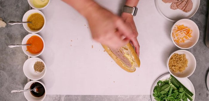 Assemble the Ultimate Banh Mi: Layer aioli, Cha Lua, pate (layered in between), pork floss, pickled vegetables, cucumber, cilantro, basil, scallions, fresh black pepper, and hot sauce. (309.27)