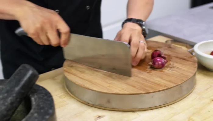 Soak Thai shallots in hot water for 10 minutes to make peeling easier. Roughly chop shallots, garlic, chili, and lemongrass. Pound these ingredients in a pestle and mortar to create a paste.