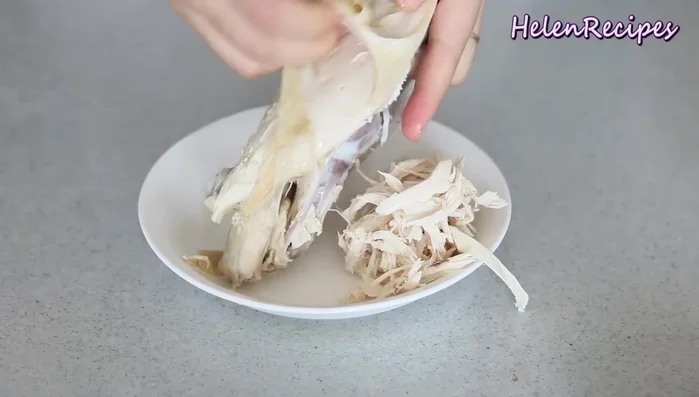 Cook the chicken until tender, then let it cool completely. Remove the skin and shred the chicken by hand into strips.