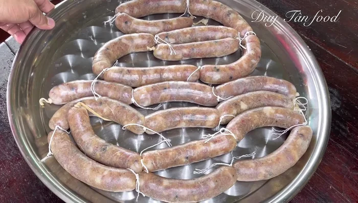 Briefly dip the sausages in hot water mixed with green rice wine (60-70°C) for 30 seconds to disinfect and prevent souring. Prick each sausage with bamboo toothpicks to release excess water.