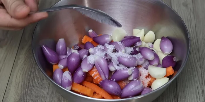 In a separate bowl, combine the carrots, onions, garlic, a tablespoon of sugar, a teaspoon of salt, and three tablespoons of vinegar. Mix well.