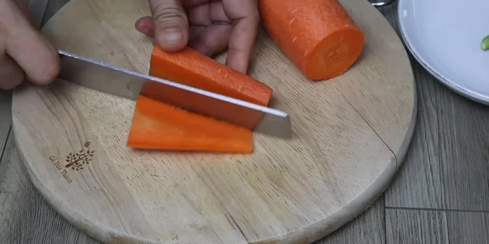 While boiling, cut the carrots into thin slices, then into smaller, edible pieces.