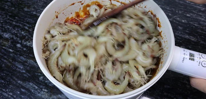 Add the shrimp to the mixture, ensuring it's fully submerged. Add a tablespoon of white wine and mix gently.
