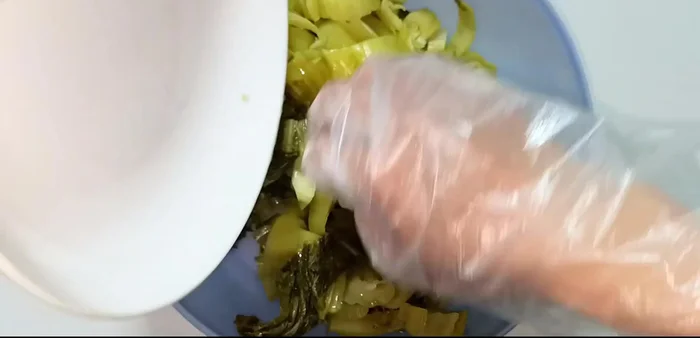 In a bowl, combine the chopped pickled cabbage, sugar, minced garlic, and chili peppers.