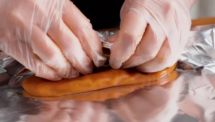 Place a whole pig ear on aluminum foil, add smaller pieces inside, and tightly roll. Wrap both ends.