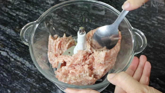 Grind the ground pork with green onion, cilantro, shallots, fried onions, pepper, fish sauce, seasoning powder, and sugar in a mortar and pestle.