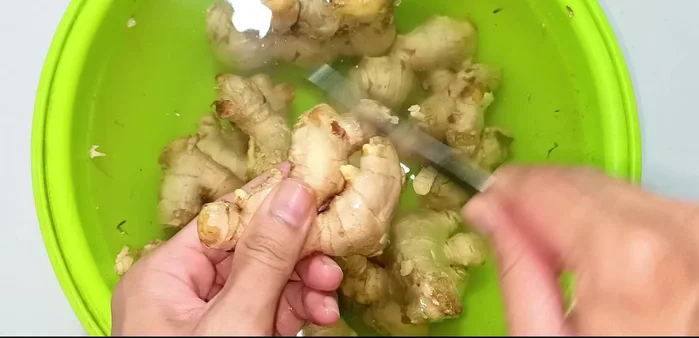 Peel the ginger using a spoon and/or knife, carefully scraping off the skin. Prepare another bowl of water with salt and half a lemon to clean the peeled ginger (prevents discoloration and reduces spiciness).