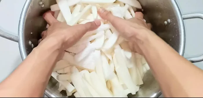 Place the sliced radishes in a large bowl and add three tablespoons of salt. Mix well and let it soak for 4 hours, mixing occasionally to help the radishes release their water.