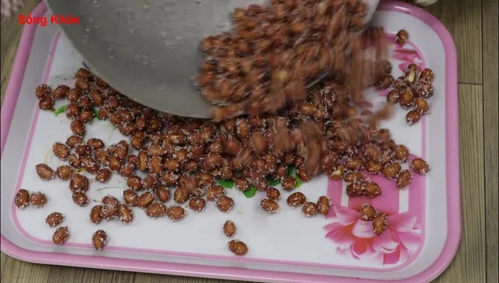 Pour roasted peanuts onto a tray or wooden spoon to cool down and prevent sticking. Stir occasionally.