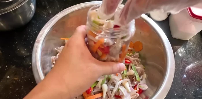 Pour the remaining vinegar solution over the pig's hands, ensuring they are fully submerged.