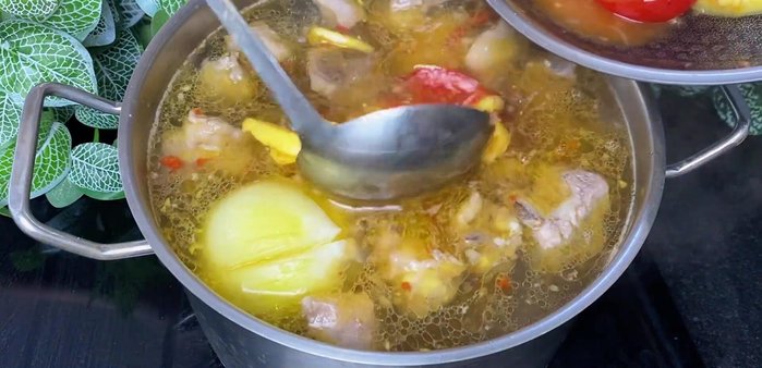 Add the stir-fried pineapple and tomatoes to the simmering broth.