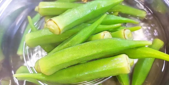 Remove okra from heat and let it cool slightly. Then, cut off the stem and separate the okra into four parts.