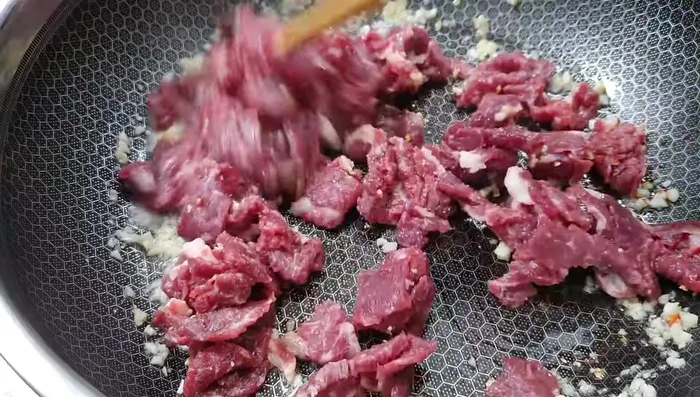 Add the marinated beef to the pan and stir-fry until cooked.