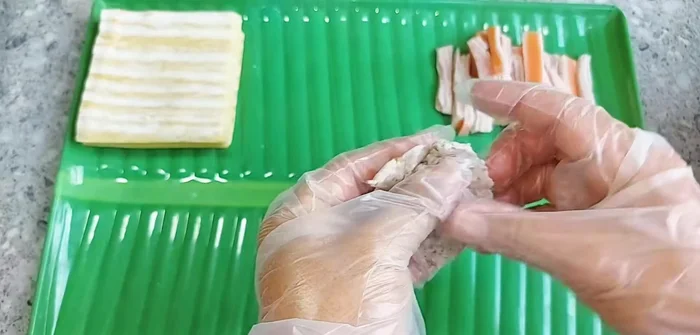 Assemble the spring rolls: Take a small amount of the taro mixture, place a piece of crab stick in the center, and spread the taro evenly around it. Squeeze firmly to compact the filling.
