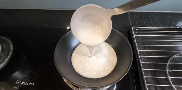 Bake the cake: Pour batter into a thick-bottomed pan, bake for 2-3 minutes on low heat, cover, and cook for another 4-5 minutes. Add coconut filling to the top.
