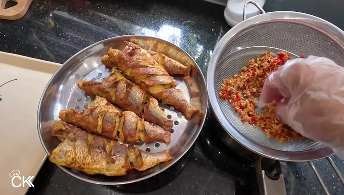 Remove the fish from the pan, garnish with crispy lemongrass and chili, and serve. (315.56, 324.28)