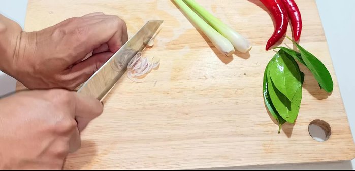 Cut the remaining lemongrass diagonally into thin slices. Cut chili peppers and lemon leaves.