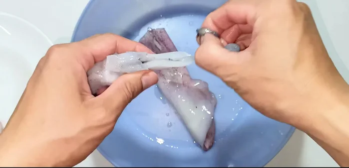 Clean the squid: Remove the head, ink sac (cut below the eyes to access it), and dorsal fin. Rinse thoroughly.