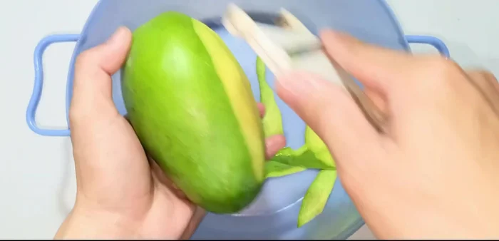 Peel and grate the green mango. Choose a mango that is moderately sweet and sour for the best flavor.