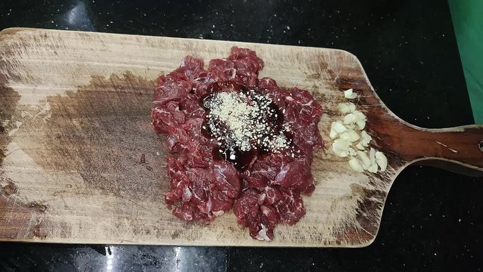 Marinate the beef with oyster sauce, a little grain (likely sugar), and cooking oil to soften it. Slice thinly and pound to break down tendons for tenderness.