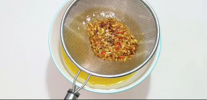 Gently stir the fried lemongrass, garlic, and chili to remove excess oil.