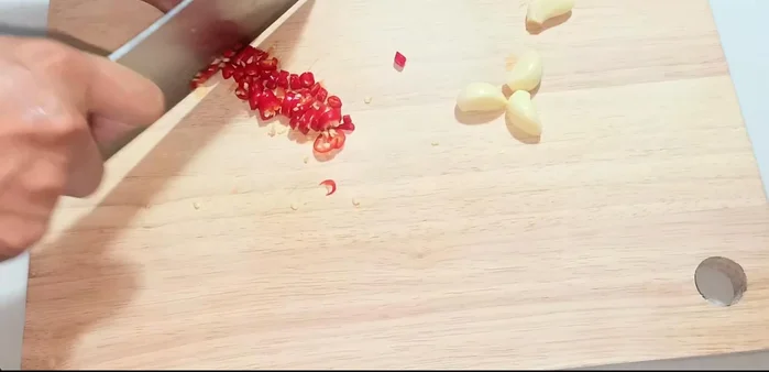 Finely chop the chili peppers, garlic, and lemongrass (using a pestle and mortar for easier chopping).