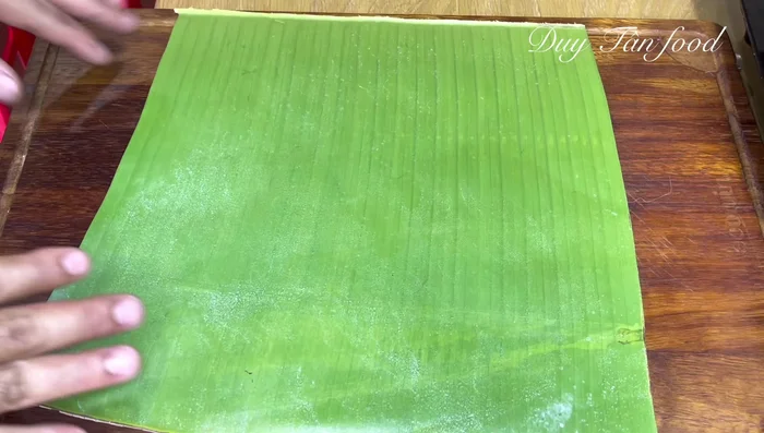 Wrap the Banh Gio: Fold the large leaf into a triangle. Place a smaller leaf on top, opposite direction. Place half of the dough in the center of the leaves, followed by filling and egg. Top with remaining dough and wrap tightly, tucking in the ends of the leaves.