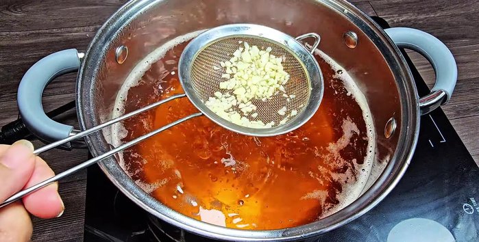 Place minced garlic in a sieve and submerge it in the simmering fish sauce for 30 seconds. Remove the garlic.