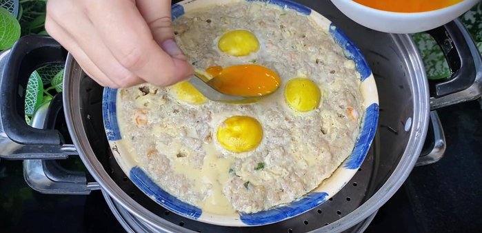 After 40 minutes of steaming, open the lid and carefully brush the egg yolk mixture on top.