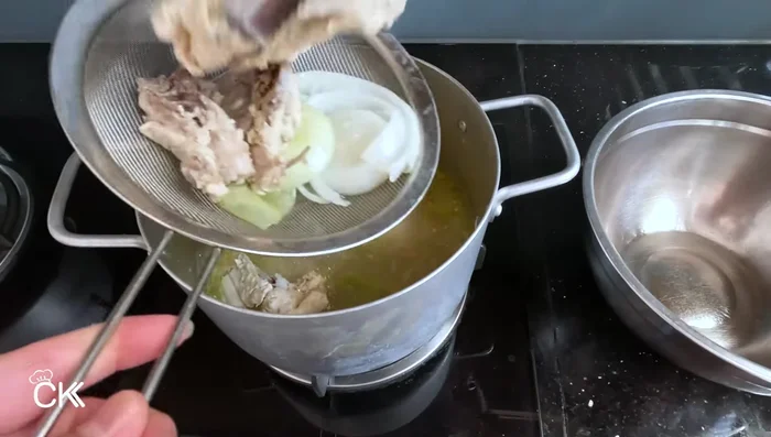 Remove chicken bones and onions, set aside. Add remaining dark soy sauce to the broth and simmer for 15 minutes until thickened.