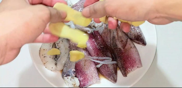 Arrange sliced ginger and chili peppers around the squid in the steamer. (162.159)