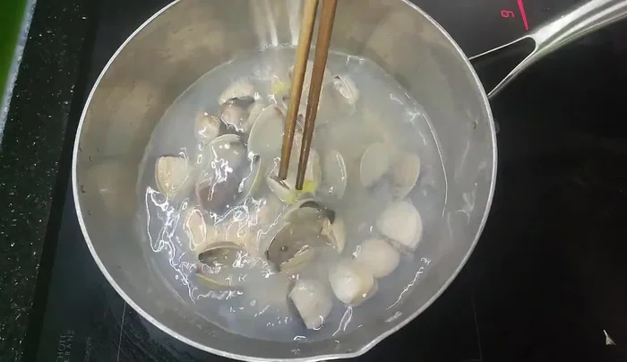 Boil water in a pot. Add clams, a slice of ginger, and a little lemongrass or salt.