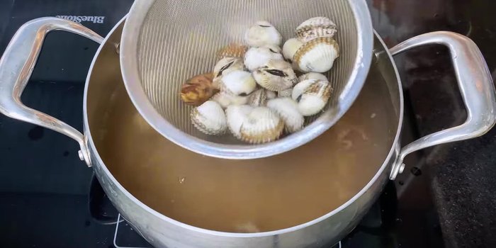Quickly scoop the cockles out using a basket to drain the water. This helps the cockles cook evenly while drying.