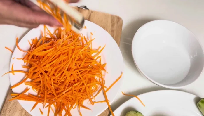 Grate carrots and shred mango.
