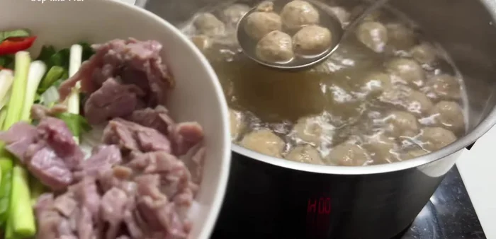 Assemble the pho: Add noodles, rare beef, beef balls, broth, and toppings (coriander, cinnamon, onion, bean sprouts, lemon, sauces).