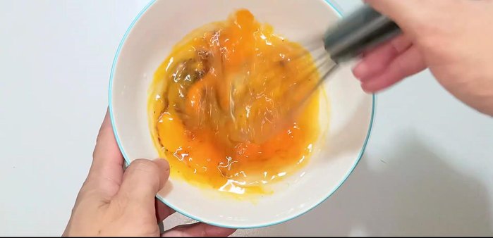 Add the sliced cabbage to the egg mixture. Mix well, ensuring the spices are evenly distributed.