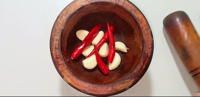 Crush 7 cloves of garlic and 5 chili peppers using a pestle and mortar until pureed.