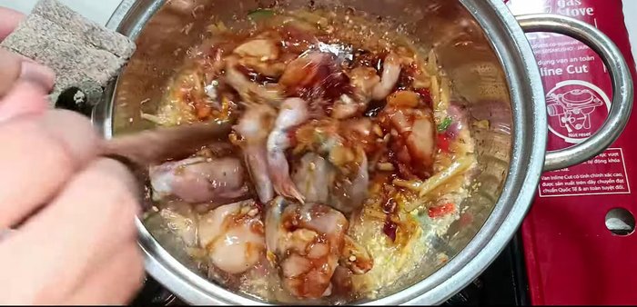 Add the marinated frog legs to the pot and stir-fry until firm.
