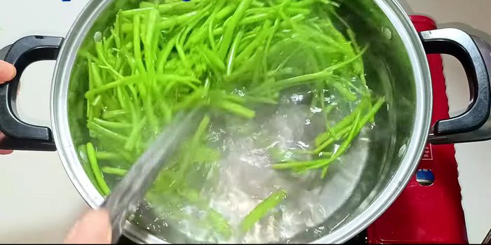 Immediately transfer the boiled water spinach to a bowl of ice water to maintain its crispness and green color for about 2 minutes.
