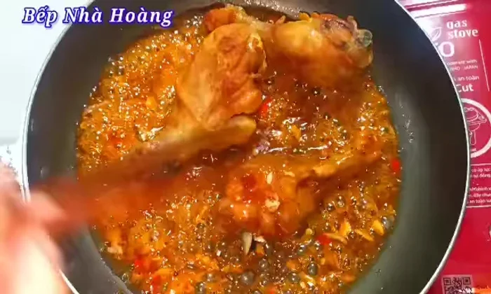 Add fried chicken thighs to the boiling fish sauce marinade. Stir gently to coat evenly, ensuring all chicken pieces absorb the sauce. Reduce heat to low and continue to cook until the sauce has coated evenly.