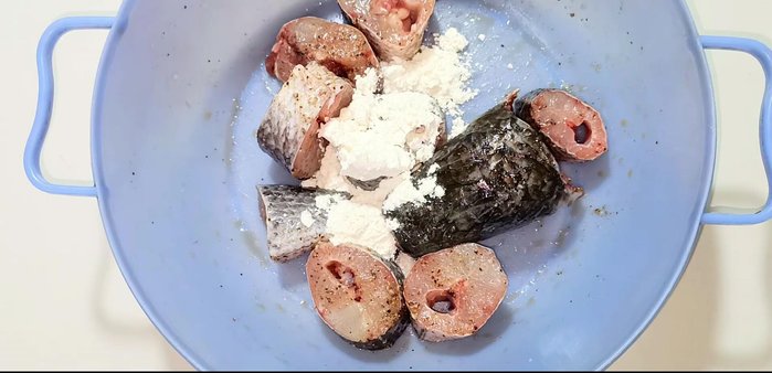 Coat the marinated fish with crispy flour, ensuring even coverage.