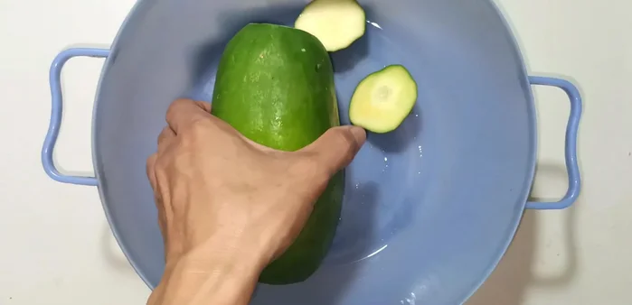 Remove the ends of the papaya and peel the skin using a double-edged knife. Choose firm papayas that are slightly yellow on the outside.