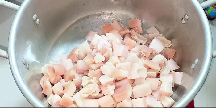 Render the fat: In a pot, add 200ml of water and the cut pork fat. Cook over medium heat, stirring frequently to prevent sticking and ensure even rendering. Continue stirring until all the water has evaporated and the fat starts to crisp up.