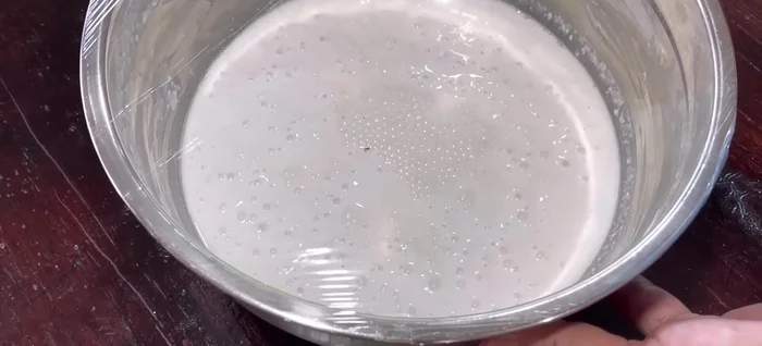 After 12 hours of fermentation, gently stir the dough. Gradually add the warm sugar water to the dough, stirring well to combine. The dough will be sticky, but don't worry.